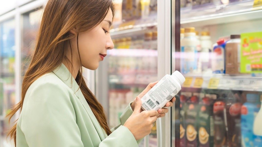 Frau studiert Etikett mit Inhaltsstoffen am Kühlregal